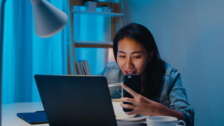 Freelance business women eating instant noodles live on social media at home at night.