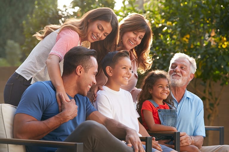 Multi-Generation Hispanic Family Relaxing In Garden At Home Together