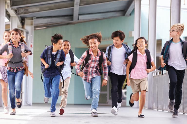 Group of elementary school kids running in a school corridor