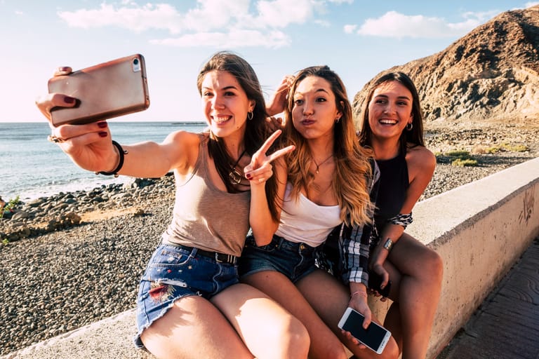 Millennial girls taking selfie picture with modern phone for social media having lot of fun together