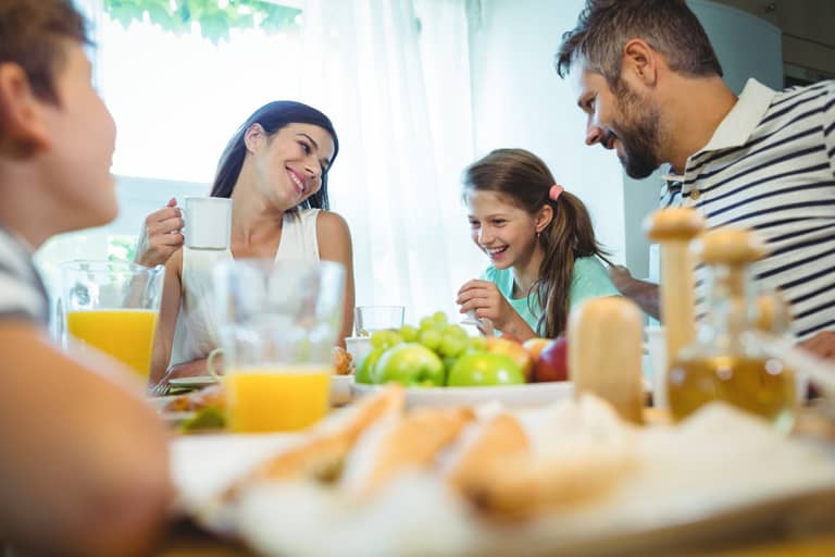 Smiling parents talking with their daughter at breakfast table