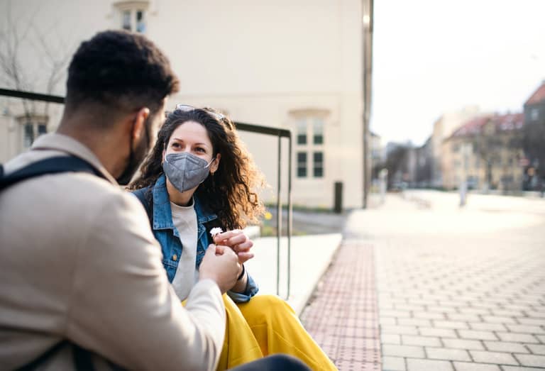 Man giving flower to woman outdoors in city, coronavirus, love and back to normal concept